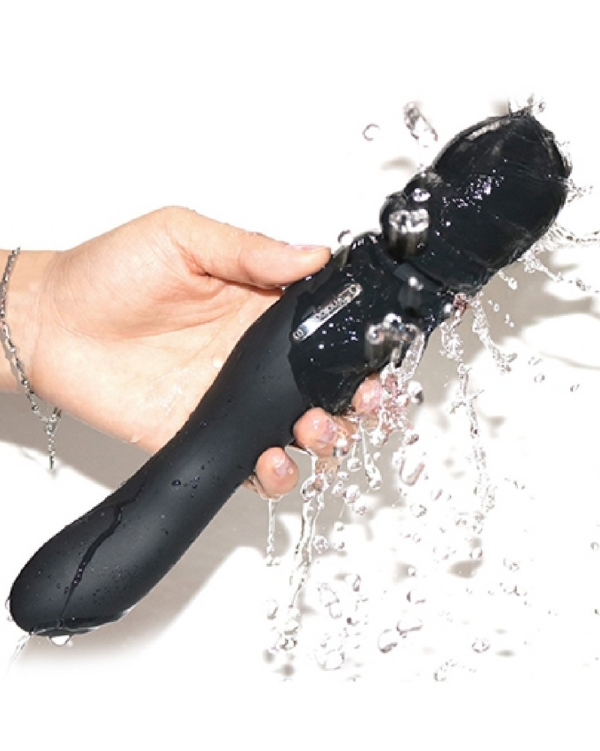 Black wand vibrator held in hand being splashed by water